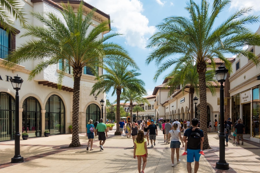 Visitors walking through Disney Springs with shops and palm trees in Orlando, Florida.
