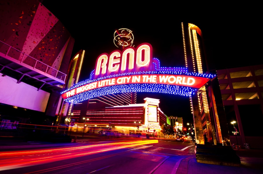Night view of the Reno Arch with glowing neon lights and 'Biggest Little City' slogan.