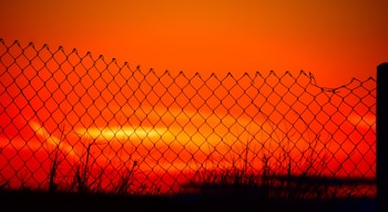 A photo taken at the top of a sand dune while the sun was setting behind a fence #culture