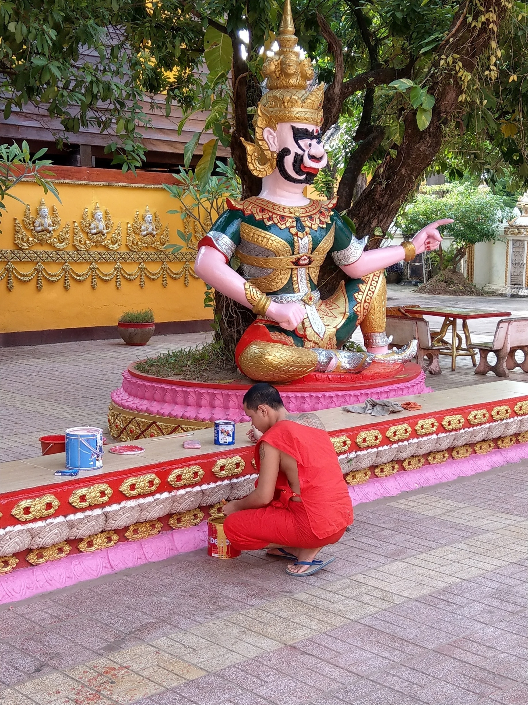 A monk touching up the gold leaf at Wat Si Muang Vientiane