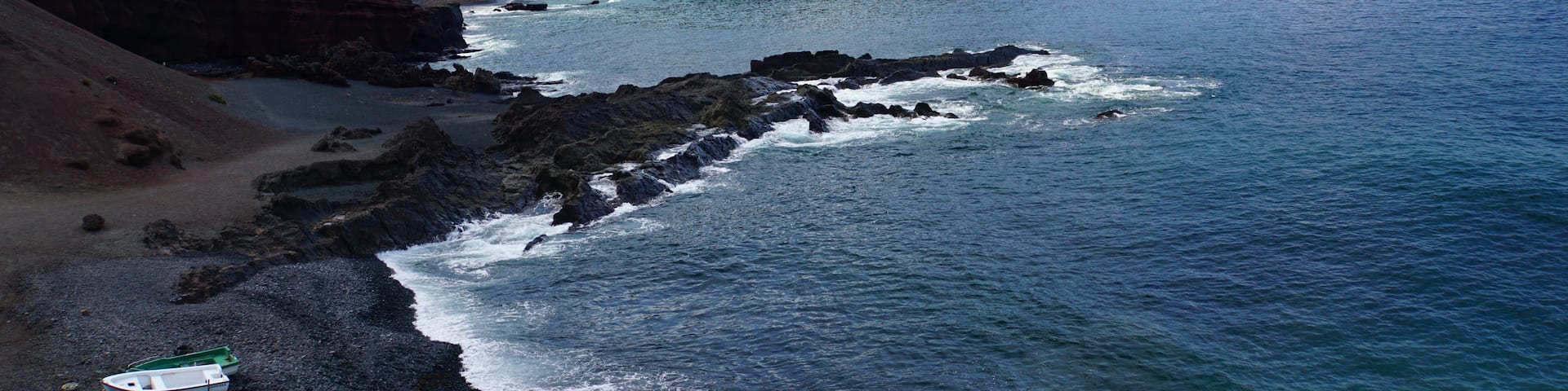 A surreal black sand beach with fishing boats on the west coast of Lanzarote – formed over centuries by the ocean from fragments of lava and other volcanic minerals - this volcanic world looks like it belongs to another planet #LifeAtExpedia #SeasideDiscoveries