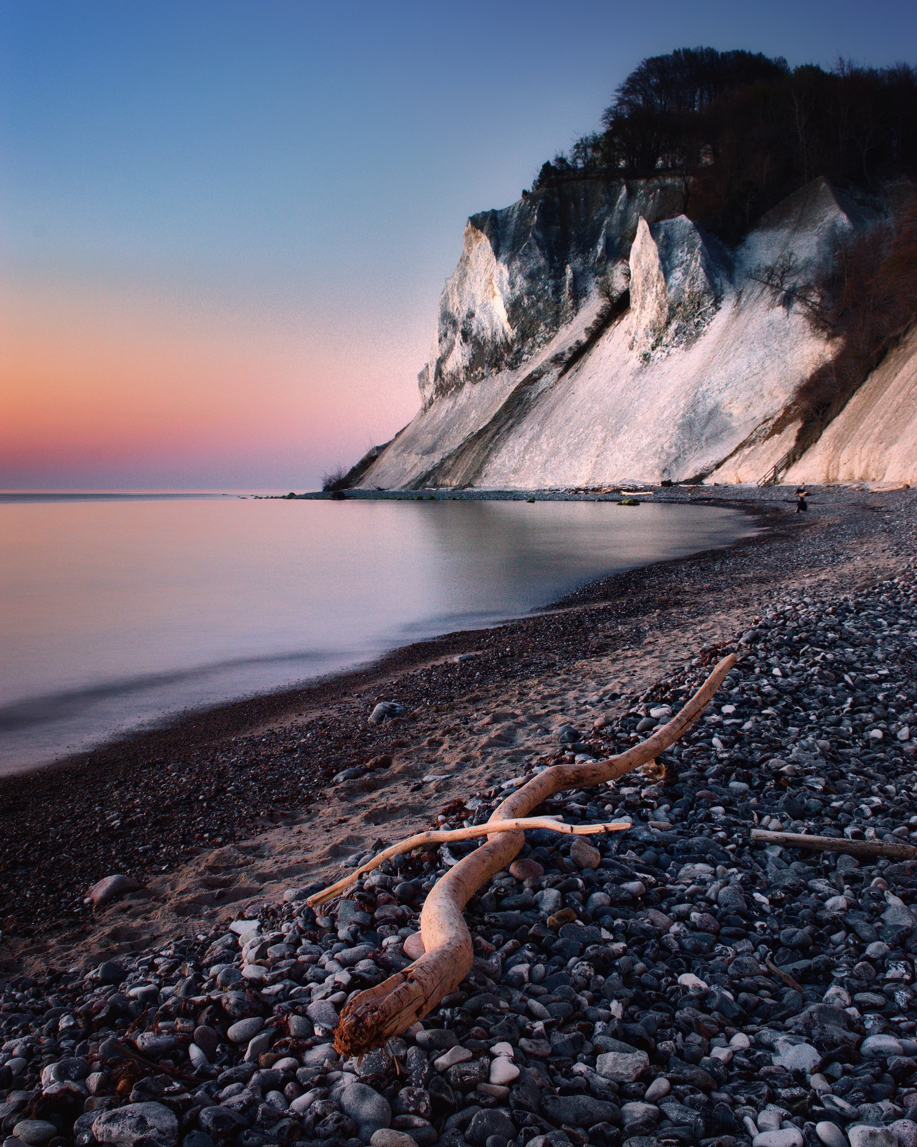 Møns Klint is a 6 km stretch of chalk cliffs along the eastern coast of the Danish island of Møn in the Baltic Sea. Some of the cliffs fall a sheer 120 m to the sea below. 
Visit the Geocenter Møns Klint in the daytime - or watch the stars on the beautiful night sky in this Dark Sky area.
#sunrise #ocean #longexposure #pebble #cliff #darksky #chalk #morning
