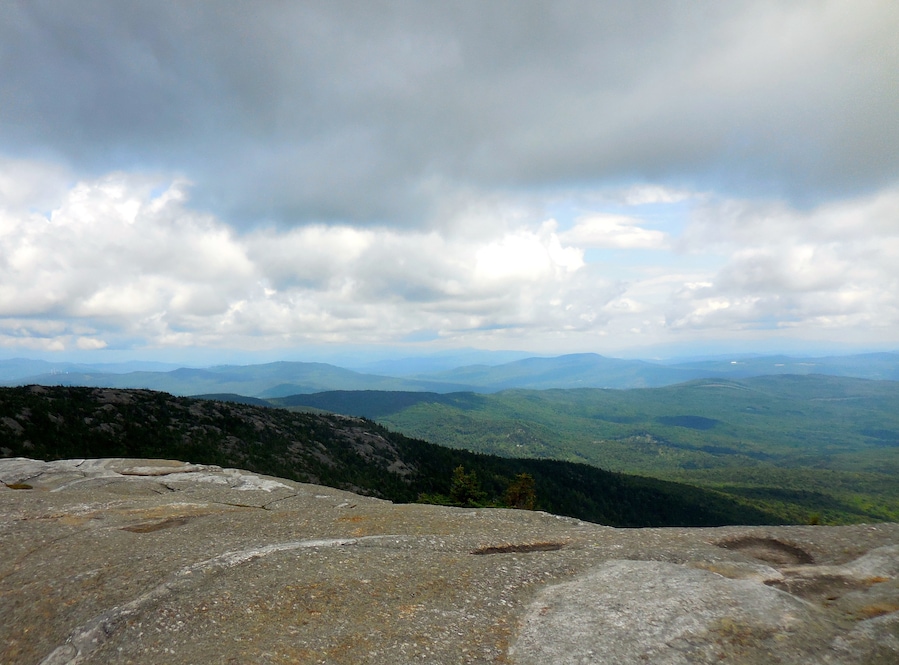 At the summit of Mt. Cardigan. A 3121 ft peak in Central New Hampshire. A moderate hike of 1.5 miles from the parking lot on the western side of the mountain. Stunning 360 degree views off of the granite, treeless summit make this an outstanding short day hike for families. It can be warm hiking up, and quite cooler with a lot a wind at the top.