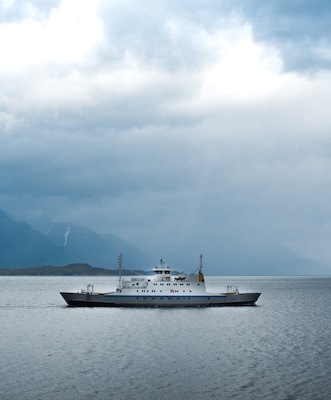 Took a break on my solo road trip to Nordkapp, and stopped the car at the side of the road on the E6 as I noticed the ferry heading across the fjord right next to me. I thought it looked pretty cool with the mountains in the background covered in clouds. and a ray of sunshine lighting the vessel.