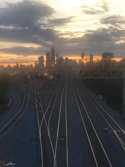 Railway tracks with Charlotte skyline in the background during sunset.