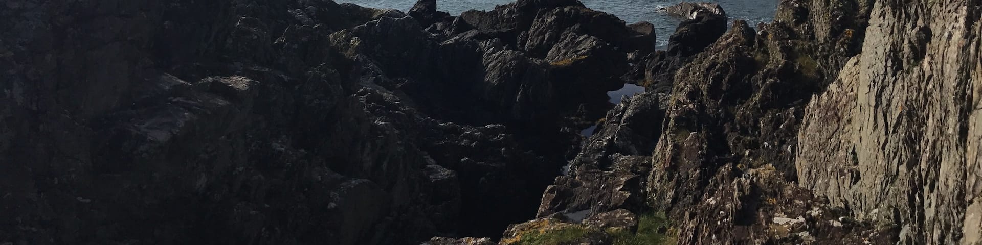 A lonely fisherman in his boat sheltered by the crags.