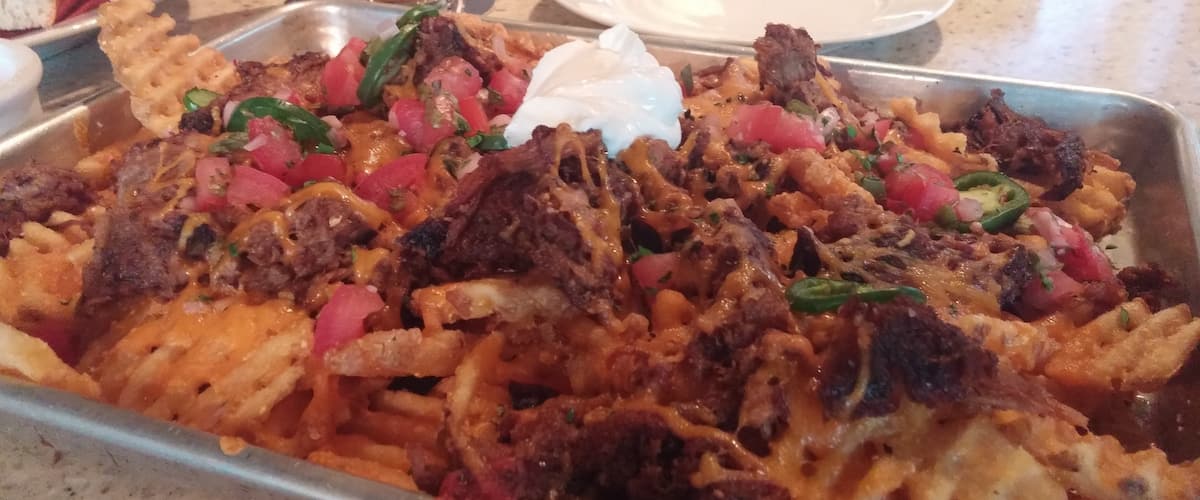 Waffle nachos!
Masa-crusted waffle fries topped with smoked pulled pork, cheddar cheese, salsa, jalapenos, cilantro and sour cream.