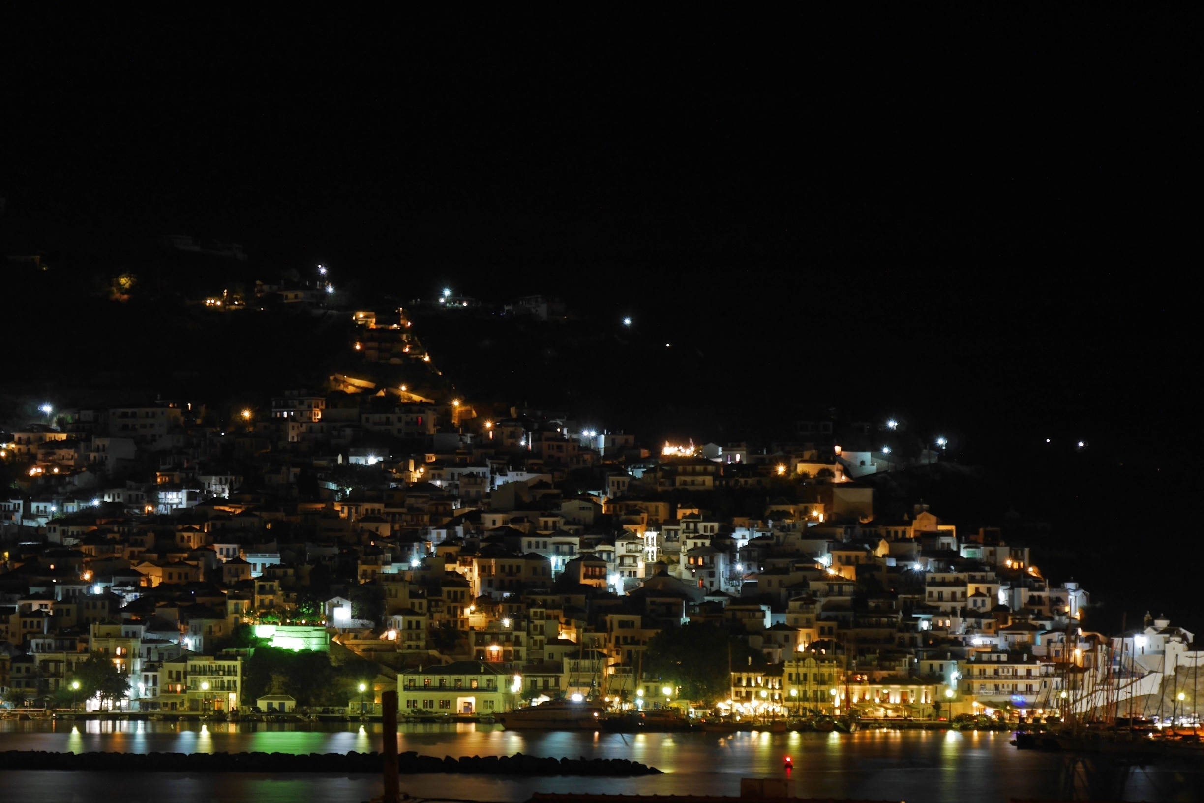 Skopelos Town by night.  Skopelos is a wonderful Greek island with an authentic feel and most certainly my favourite.  Reputed to be the greenest of all the Greek islands it is covered in pine forests.
It is also relatively unspoilt as it does not have an airport & is not the easiest island to get to.  Like nearly all the islands however it can get busy at the height of the summer.
The main town tumbles down to the harbour through a mass of narrow streets where rubbish is still collected by mule. The tavernas abound with live music & several well known Greek musicians live and/or perform regularly here.