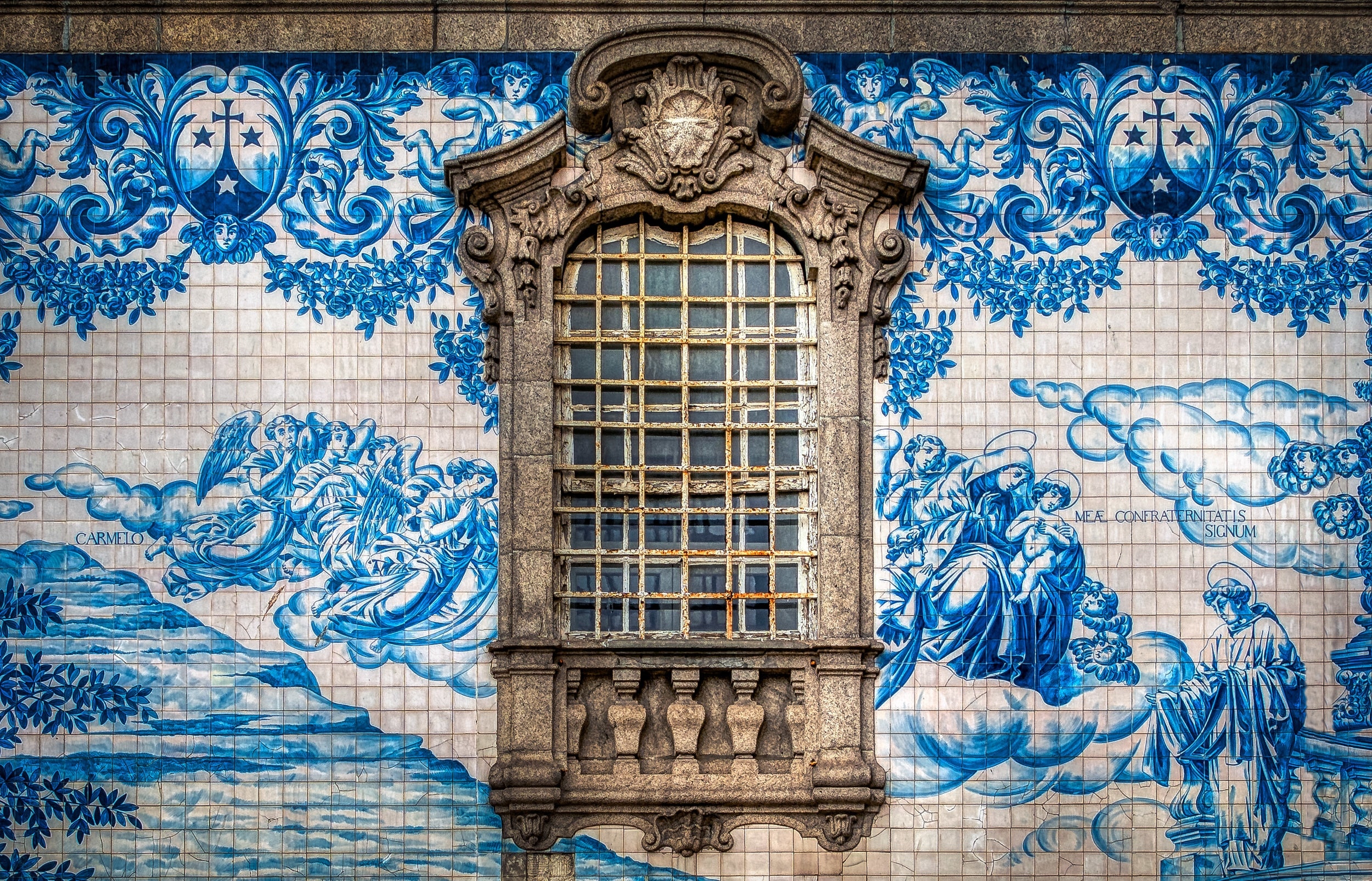 "Azulejo" is a form of Spanish and Portuguese painted tin-glazed ceramic tilework. Azulejos are found on churches, palaces, ordinary houses, schools, and nowadays, restaurants, bars and even railways or subway stations. They were not only used as an ornamental art form but also had a specific functional capacity like temperature control in homes. I photographed this beautiful artwork outside of the "Igreja do Carmo" church in Porto, Portugal.