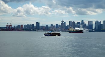 A Seabus heading toward downtown Vancouver crossing the Burrard Inlet on an overcast day.  This is a regular passenger-only ferry service that crosses from Lonsdale Quay in North Vancouver to Waterfront Station in Vancouver. The journey takes around 10 to 12 minutes. This photo is taken from another Seabus looking back toward a Vancouver skyline.