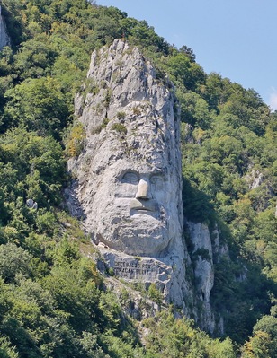 Decebalus is considered a national hero in Romania and has been portrayed in numerous literary works, movies, public sculptures, and other memorials.
The rock sculpture of Decebalus (Romanian: Chipul regelui dac Decebal) is a 42.9 m (141 ft) in height and 31.6 m (104 ft) in width carving in rock of the face of Decebalus (r. AD 87–106), the last king of Dacia, who fought against the Roman emperors Domitian and Trajan to preserve the independence of his country, which corresponded to modern Romania.
The sculpture was made between 1994 and 2004, on a rocky outcrop on the river Danube, at the Iron Gates, which form the border between Romania and Serbia. It is located near the city of Orșova in Romania.
It is the tallest rock relief in Europe.
The project of sculpting the colossal head of Decebalus was the brainchild of a wealthy Romanian businessman, Iosif Constantin Drăgan. In 1985, Drăgan chose the rock to be sculpted, an outcrop 128m in height located in the area of Iron Gorge, Danube. Perhaps one of the reasons Drăgan chose this site was due to the fact that the Tabula Traiana, a memorial to the Roman conquest of Dacia, was located on the opposite side of the river.
After the sculpture was completed Latin inscription was put beneath it and is: DECEBALUS REX DRAGAN FECIT, which meant “King Decebalus, made by Dragan”.
The best photographs are made while cruising if you are visiting from serbian side or from a bridge if you are already in Romania.
#InStone
#History
#Romania
#Serbia
#Danube