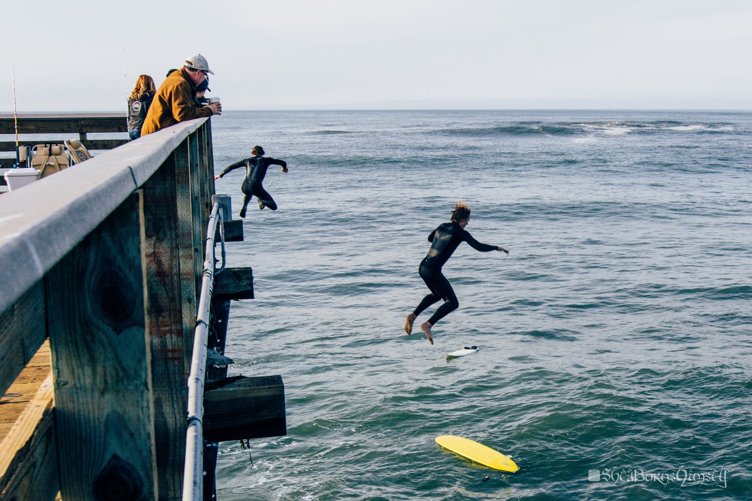 Surfers jumping off the pier.