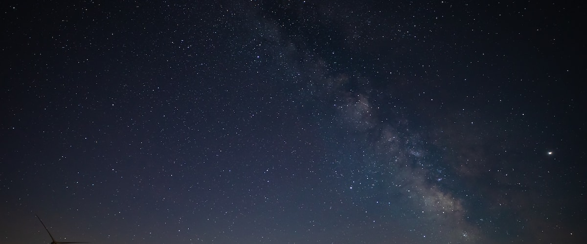 Milky Way photographed on clear sky night near a wind farm