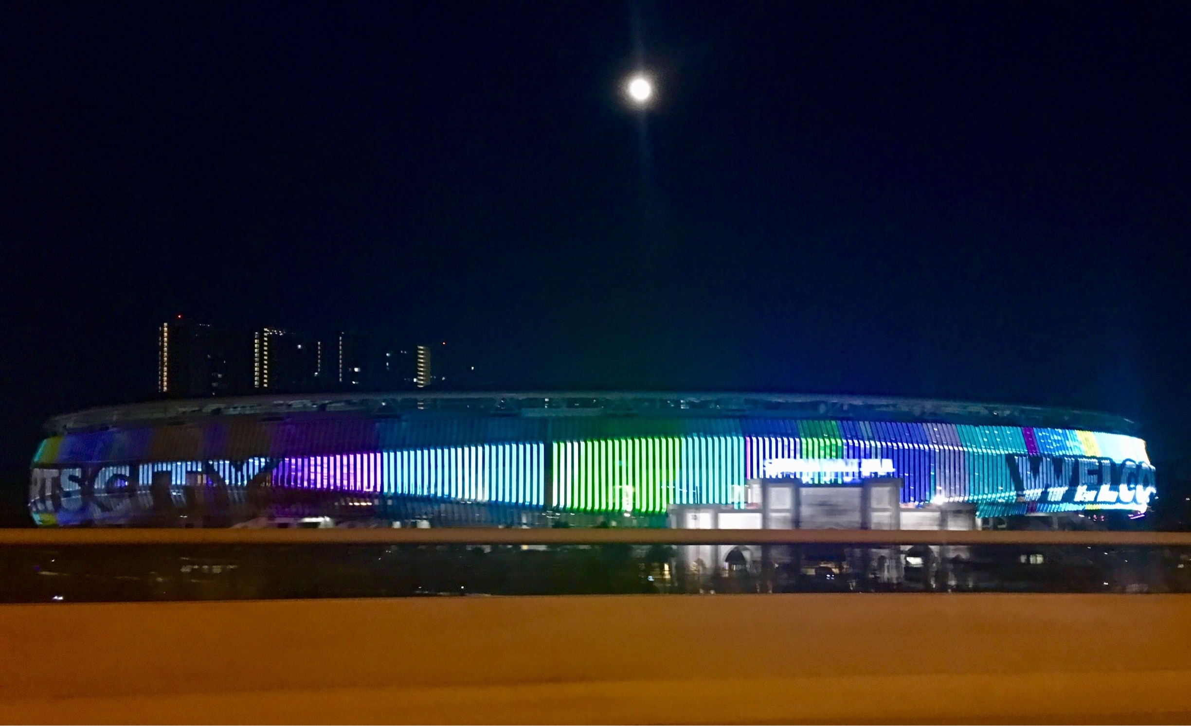 The playful display of colourful LED lights illuminate KL Sports City as the full moon illuminates the sky above it. #klsportscity.my #stadium_bukitjalil #dusk #led display #led #kualalumpur #malaysia #travelblogger #mariadasstheworld