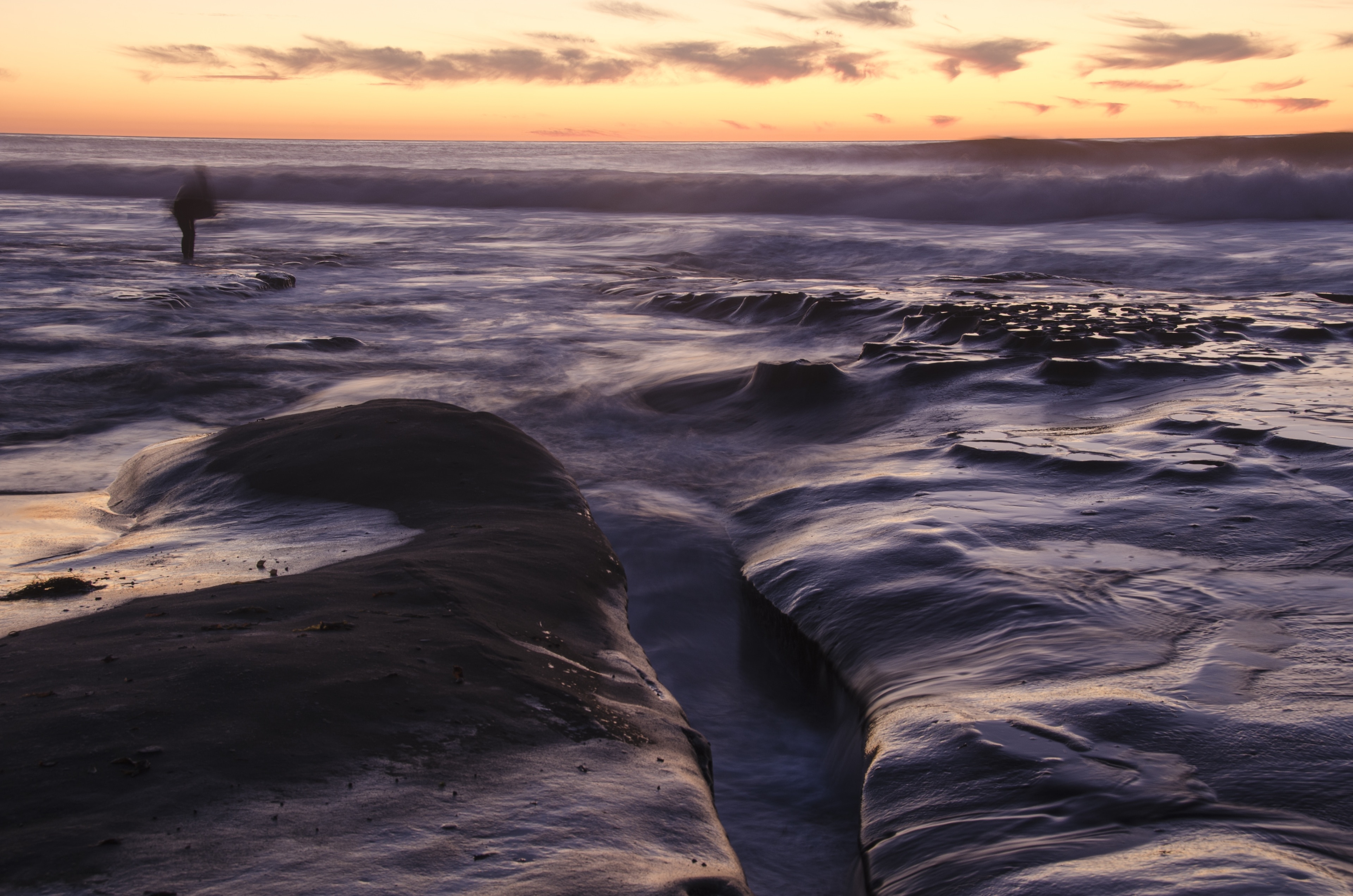 As the sun goes down in La Jolla, the water flows into the rocky areas, covering up most of the tide pools.  When photographing this scenery, a person walked on the tide pools, preparing to go into the water and surf.  One of the most interesting things that happened in this image is the way the river pours into the tide pools and then recedes back, repeating this over and over again, while people tend to walk over them, either to photograph or to swim.

#myBackyard #Trovember #LaJollaTidepools #LaJolla