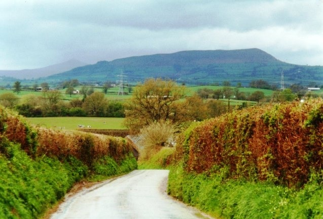 East of Llantilio Crossenny The Offa's Dyke Path takes a varied route through low farmland between Monmouth and Pandy. Here is one of the welcome road sections; welcome if the fields are waterlogged as they on this day. Ysgyryd Fawr is always in view ahead (except when covered in mist).