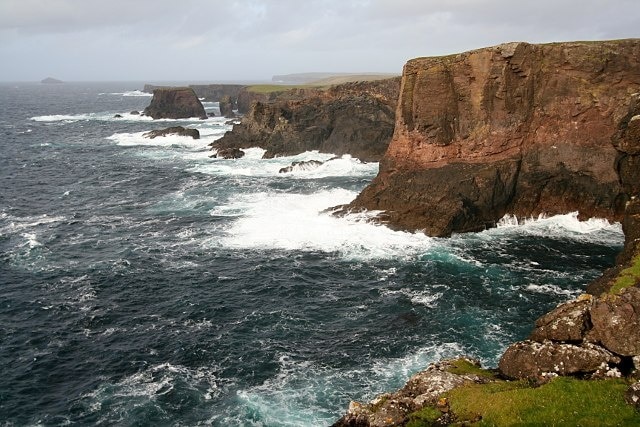 Esha Ness as the storm approaches We had hoped to paddle this coast during our week in September, but winds were high all week. In this evening view the cliffs are already being battered by swell from a storm which would not arrive for another thirty hours. Waves which are "only" a couple of metres in this view were forecast to rise to four and a half metres the next day. Understandably, we paddled in more sheltered locations. In the right conditions, sea kayakers can get in amongst the cliffs and stacks, where there are several subterranean passages. Even with swell (but without the strong winds) we could contemplate making the passage between Moo stack (upper left) and the main cliffs, and perhaps visiting Muckle Ossa, the small island top left. It will all be there for next time ...