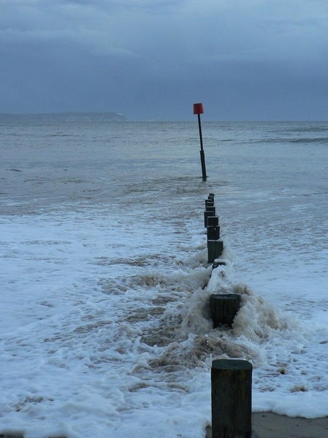 The waves pound the groyne The waves of the incoming tide cascade over the uprights of a groyne on this very windy day.