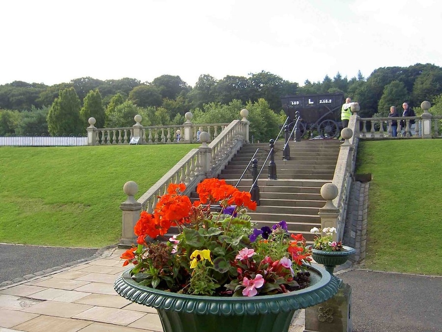 Beamish Museum, County Durham, England. The view south up the steps that lead down from the car park to the south facade of the entrance building (behind the camera), in the entrance area of the museum site. At the top of the steps is the chaldron wagon mounted on a plinth as a static exhibit.
