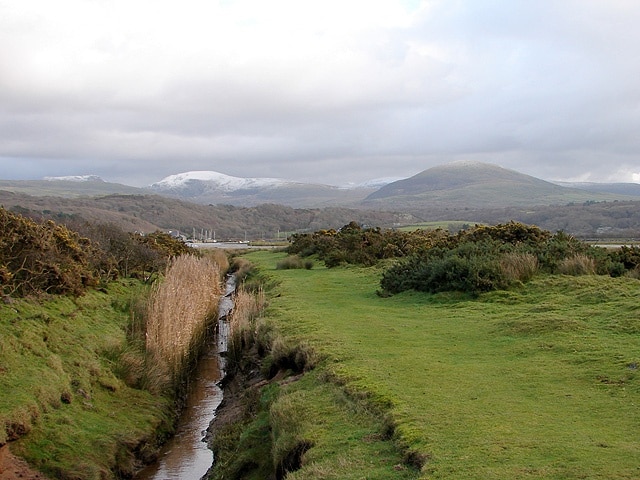 Drainage channel at Ymwlch The Artro Estuary can just be seen running across the centre of the view and beyond that the Rhinogs have a light dusting of snow.