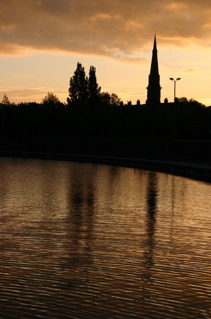 Sunrise over Failsworth, in Greater Manchester, England. The steeple is of St John the Evangelist's parish church. The waters are that of the Rochdale Canal.