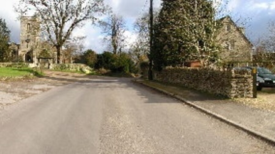 Photo "Approach to All Saints Church, Crudwell. I think the building on the left is the Old Rectory Country House. The ancient church straight ahead is All Saints Church. This is the view that you get as you leave the main road coming from The Mayfield House Hotel." by Kenneth Allen (Creative Commons Attribution-Share Alike 2.0) / Cropped from original