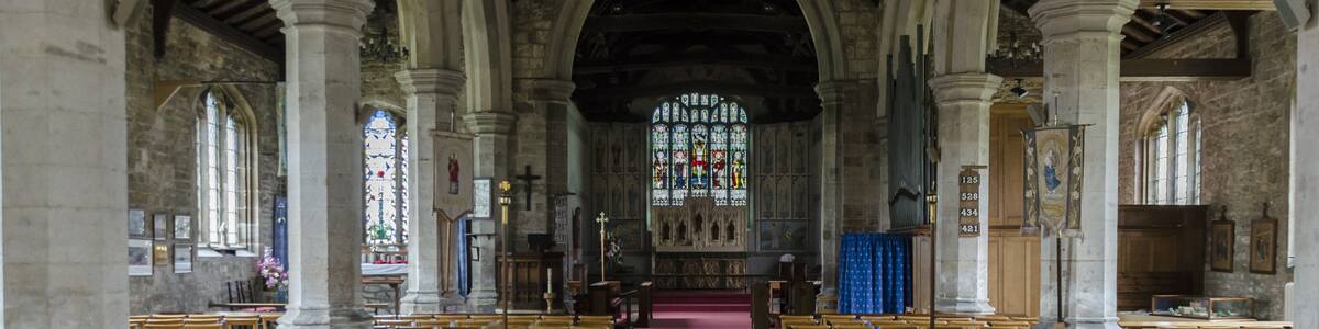 Photo "Interior. Note the painted chancel. The church was built around 1434, with restoration in the 1870s. It consists of a nave with aisles, western tower, chancel, and north porch. Some parts of the demolished Bardney abbey were used in the church. The tower dates from the late 15th century and has battlements topped with eight pinnacles. It has six bells. The north aisle of 5 bays is from the mid-to late 15th century, the south aisle is of the same date. The piers are octagonal. There is a 17th-century north porch with benches. The chancel is made of brick; Some say the same bricks used to build Tattershall Castle. Inside are murals of 1935 by A. Willets depicting Saints, and there are carved angels in the roof timbers. There is a 19th-century reredos and a 15th century piscina in the south wall. There is also a 14th century figure originally from Bardney Abbey. At the west end of the nave is an incised slab to Abbot Richard Horncastle, died 1508, and three painted wooden panels recording charitable donations. The font and choir stalls are 20th century. There are several architectural fragments from Bardney Abbey on display. The two manual organ is by Cousans. Restoration work was carried out in the 1870s at a cost of some £2500, during which the west end of the north aisle was formed into a baptistery. Further restoration was done in the late 1990s." by Jules & Jenny (Creative Commons Attribution 2.0) / Cropped from original