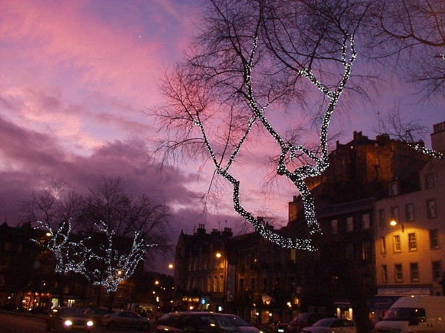 The Grassmarket at Christmas. Lights in the trees add a festive air to the Grassmarket at Christmas-time. Edinburgh Castle, floodlit, towers above the shops and pubs.