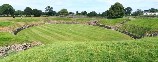 Roman amphitheatre at Caerleon. A panoramic shot showing the full size of the pit. The dot in the middle is someone sitting down. Just earlier a family who had bought plastic swords here 295725 were having a small battle on the grass.