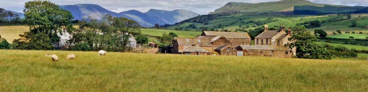 Photo "Eastward towards Ennerdale from near Cleator Moor. A fine panorama of the mountains around Ennerdale, seen from just off the B5294 Cleator - Frizington road at Threapthwaite. To the left is Murton Fell (1,461 ft.), Blake Fell (1,626 ft.), then Great Borne (2,018 ft.) and Starling Dodd (2,077 ft.) shining in sunlight NE of Ennerdale Water, while rather nearer on the right is Grike (1,556 ft.) joined to the Ennerdale Fells which line the south side of Ennerdale Water." by Ben Brooksbank (Creative Commons Attribution-Share Alike 2.0) / Cropped from original