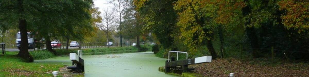Photo "Blunder Lock On the Stroudwater Canal, right alongside the busy A419. Currently home to a family of swans and two ducks." by Jonathan Billinger (Creative Commons Attribution-Share Alike 2.0) / Cropped from original