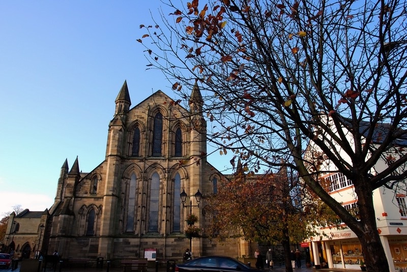 Hexham Abbey from market. The buttressed east end of the church illuminated by two triplets