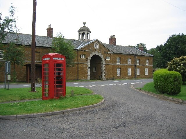 Eastwell village centre, Leicestershire. The old coach house and stables of Eastwell Hall have been converted into two houses, one either side of the coach arch.