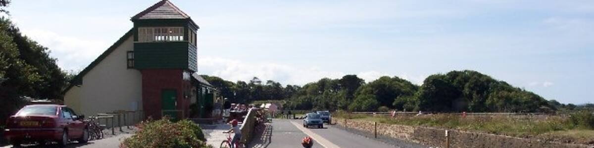 Photo "Fremington Station on the Tarka Trail. Two miles from Barnstaple the Tarka Trail comes to Fremington, which has seen a massive transformation in recent years. Once Devon's second busiest port much of the china clay produced further south was shipped out through here Fremington had become almost derelict, with an abandoned cottage the only building in sight. Now there is a visitor centre with a café and cycle hire base, and a replica (the original actually stood on the opposite platform) of the tall signalbox has been built; its height was intended to give the signalman a good view over the quayside sidings." by Ron Strutt (Creative Commons Attribution-Share Alike 2.0) / Cropped from original