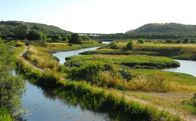 The Neath Canal and the River Neath. The Neath Canal near Giant's Grave with a tidal inlet of the River Neath to the right. The bridge in the background is the A48T Briton Ferry Bridge.