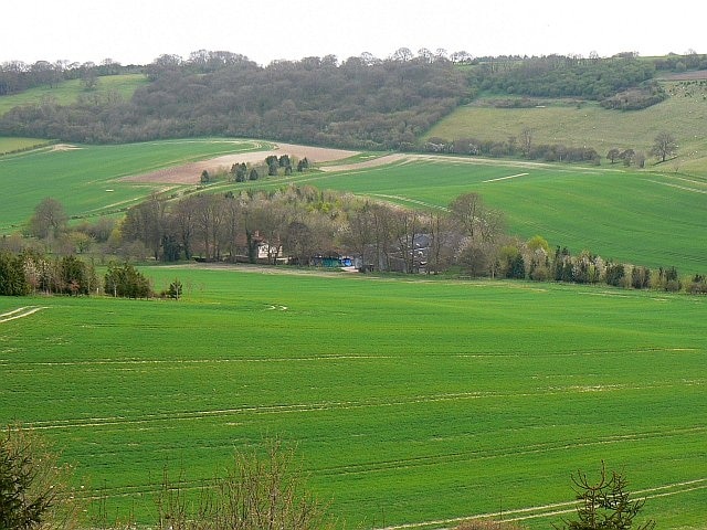 Wright's Farm, near Combe, West Berkshire Wright's Farm nestles in its own little woodland in a sheltered valley. The crops that surround it are probably cereals.