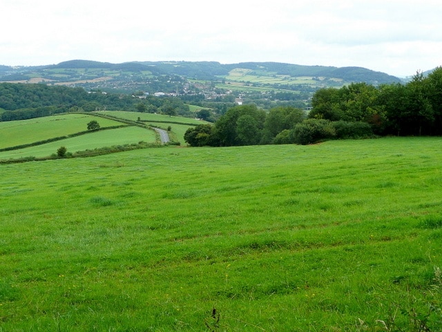 Green slopes of Lydiart Hill Looking north over the square with a section of the B4293 in the middle distance. Monmouth, in the Wye/Monnow valley can be seen below the wooded plateau of Buckholt Hill.