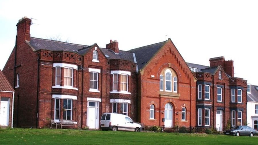 Photo "Houses at Middleton One Row A curious group of houses in Middleton. The central section looks as though it should have been a chapel, whilst the 'wings' are of a different brick. Maybe a visitor to the website can throw some light on the history of this block." by Gordon Hatton (Creative Commons Attribution-Share Alike 2.0) / Cropped from original