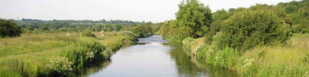 Photo "River Gade through Croxley Common Moor Viewed looking downstream with Croxley Common Moor to the left, the Grand Union Canal and the river run parallel to one another here and the canal is just beyond the hedge to the right." by Nigel Cox (Creative Commons Attribution-Share Alike 2.0) / Cropped from original