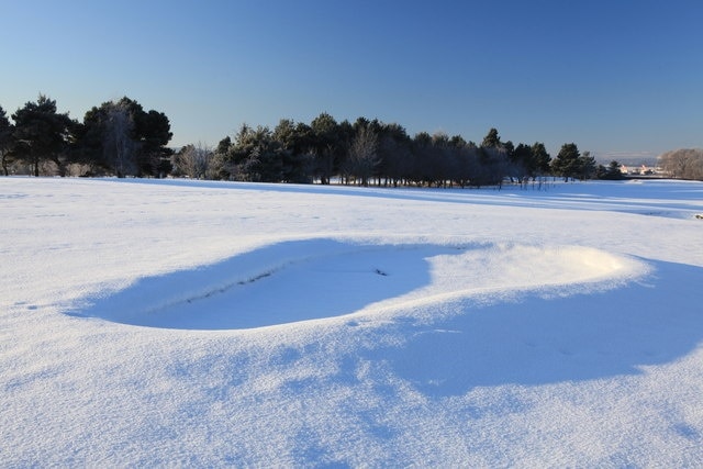 Bunker on Turnhouse Golf Course There has been no play at the course for three weeks now. The tail fins of some aircraft at Edinburgh Airport can just be made out in the distance.