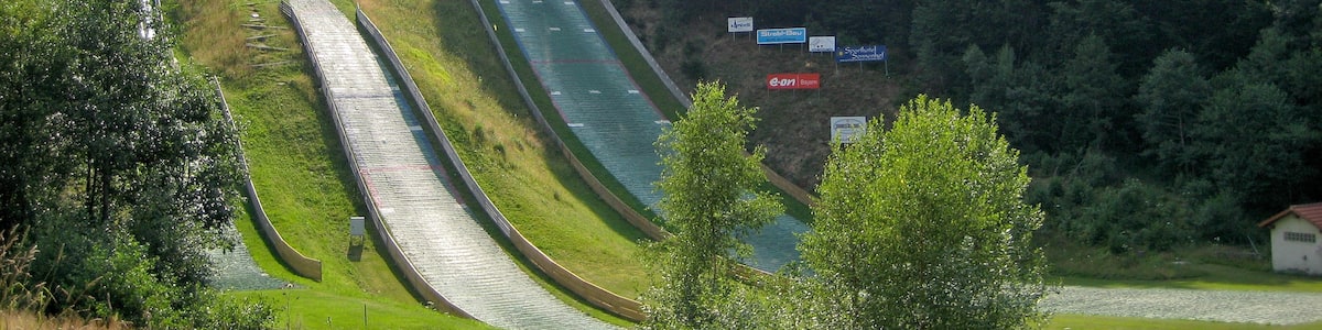Photo "Ski jumping hill of Rastbüchl near Breitenberg, Lower Bavaria" by Aconcagua (Creative Commons Attribution-Share Alike 3.0) / Cropped from original