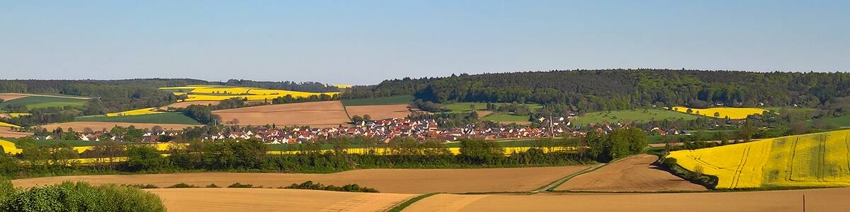 Photo "Ansicht von der Schaafheimer Warte ins Pflaumbachtal nach Wenigumstadt; rechts im Bild mit Beginn der Rapsfelder etwa die Landesgrenze Bayern - Hessen" by Commander-pirx (Creative Commons Attribution-Share Alike 4.0) / Cropped from original
