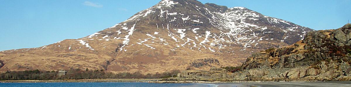 Photo "Sandy Traigh Bhan Lagain. The part of Traigh Bhan Lagain south of the little headland is much more of a classic sandy beach than the northern part 1751168. Whilst the weather is calm under a high pressure area, with blue skies, sunshine and very little breeze, the snow on Ben Buie beyond is reminder enough that winter is not really over, and clear skies bring sharp frosts at night. Even at twenty past ten on this bright morning, it was quite chilly !" by Andy Waddington (Creative Commons Attribution-Share Alike 2.0) / Cropped from original