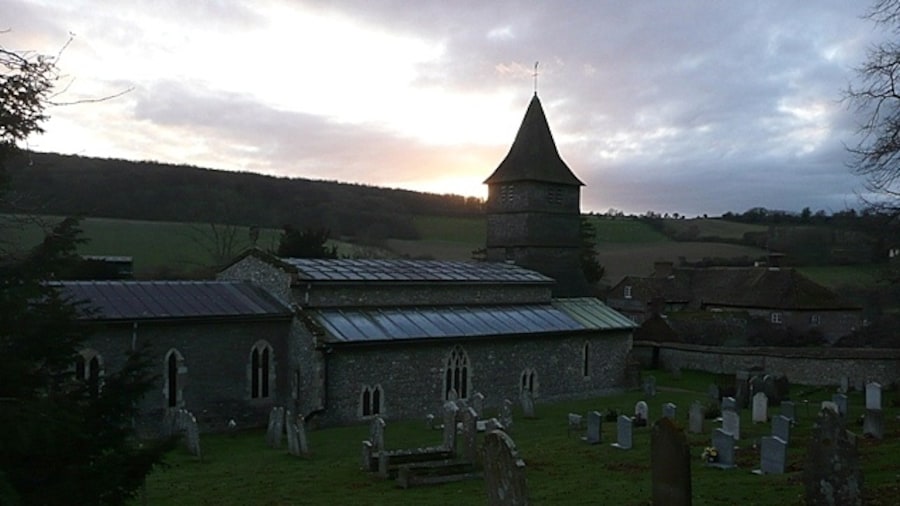 Photo "St. Peter's church, Hurstbourne Tarrant The north side from the steeply rising churchyard with the sun setting over Wallop Hill Down behind. The 17th century clerestory roof is clearly seen from this angle, as is the 15th century three-stage weatherboarded bell tower. There is more information here http://www.astoft.co.uk/hurstbourne.htm" by Graham Horn (Creative Commons Attribution-Share Alike 2.0) / Cropped from original