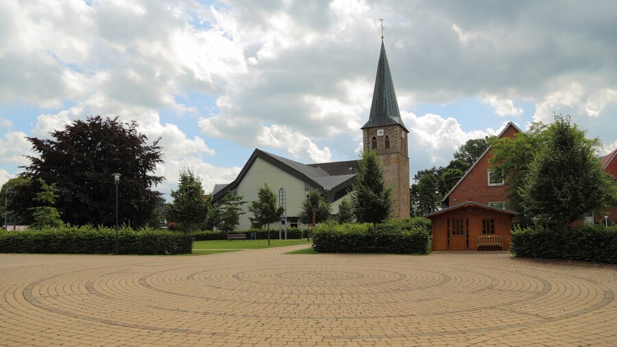 Photo "So called „Ecumenism Midst“ (Ökumenische Mitte) in Baccum, a city district of Lingen (Ems), Landkreis Emsland, Lower Saxony, Germany. The square is situated between the Reformed Church and the Roman Catholic St. Antonius Church." by J.-H. Janßen (Creative Commons Attribution-Share Alike 3.0) / Cropped from original