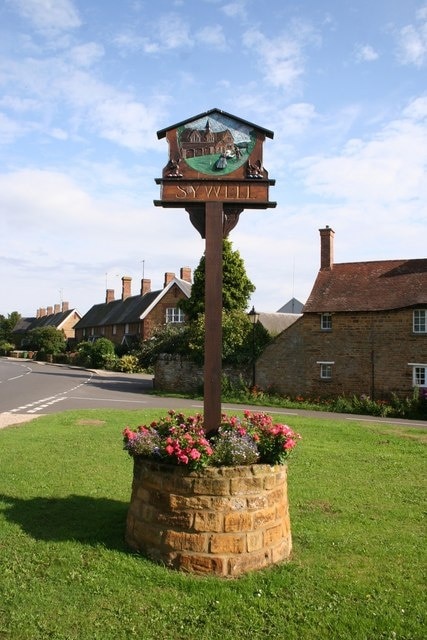 Sywell Village sign and estate cottages behind