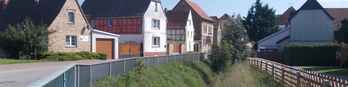 Photo "Magdeburger Strasse in Riestedt (Sangerhausen, Mansfeld-Südharz district, Saxony-Anhalt) with Riestedt stream" by Jwaller (Creative Commons Attribution-Share Alike 4.0) / Cropped from original