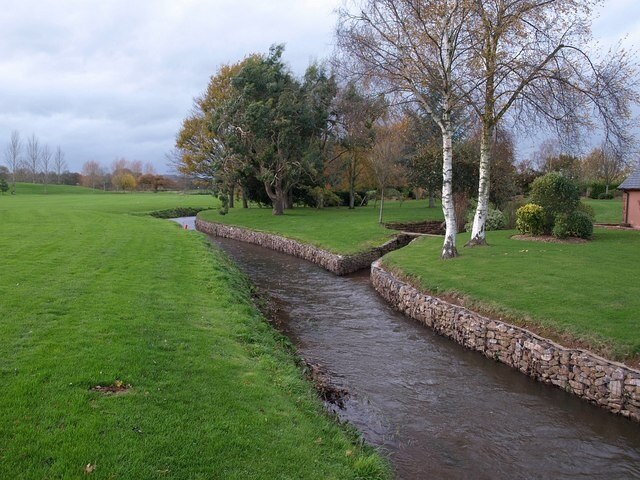 Hillfarrance Brook, Oake Footpath WG 9/19 runs alongside the brook as it flows, neatly channelled with gabions, towards the camera past Oake Manor Golf Course.