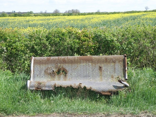 Seen better days The roadside seat on the B663 just out of Raunds looks to be suffering from advanced decay not helped by being so close to the roadside. It probably gets a good dose of salt each winter.