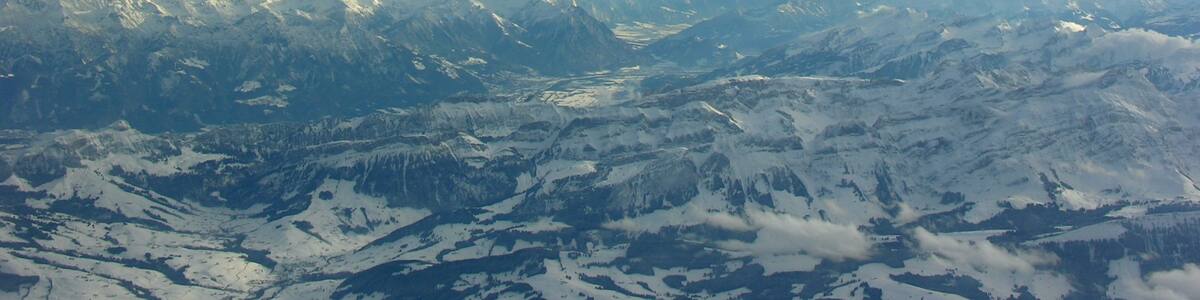 Photo "Blick über Appenzeller Land und Alpstein ins Rheintal (in der Bildmitte Triesen), im Hintergrund links das Rätikon, rechts die Glarner Alpen, am Horizont die Berninagruppe" by Simisa (Creative Commons Attribution-Share Alike 3.0) / Cropped from original